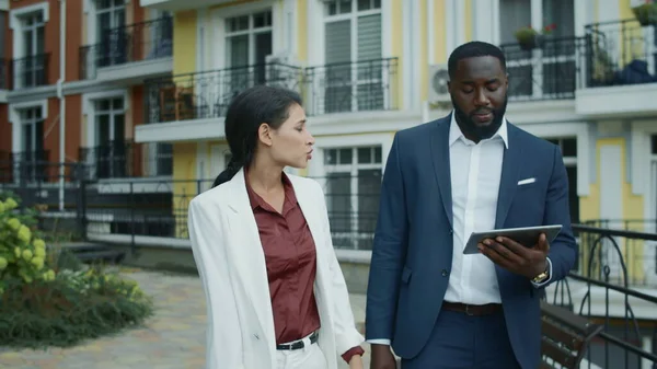 Business couple getting bad news on tablet outdoors. Afro man feeling upset