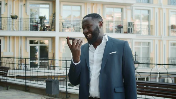 Afro guy speaking on speakerphone outside. Business man talking phone outdoors