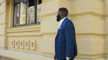 Genç işadamı aceleyle kaçıyor. Şehir caddesinde hızlı yürüyen Afro adam..