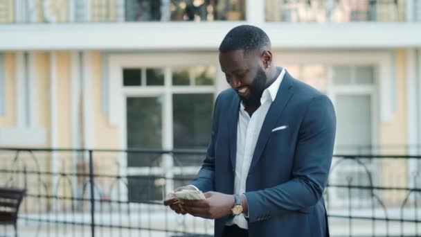 Alegre empresario africano sosteniendo dólares al aire libre. Afro chico guardando dinero — Vídeo de stock