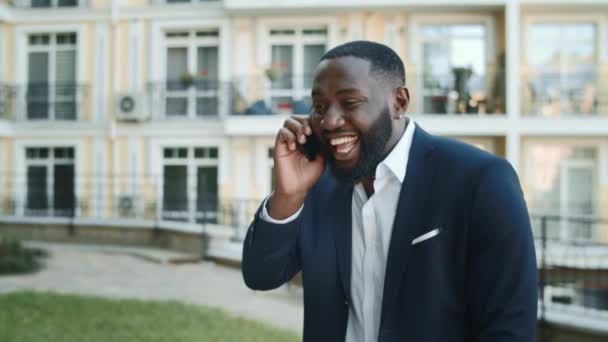 Empresário africano emocional chamando smartphone ao ar livre. Homem falando telefone — Vídeo de Stock