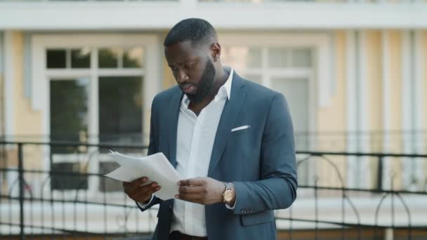 Περήφανος αφρο-επιχειρηματίας που ψάχνει χαρτιά στην ύπαιθρο. Αφρικανός που εξετάζει έγγραφα — Αρχείο Βίντεο