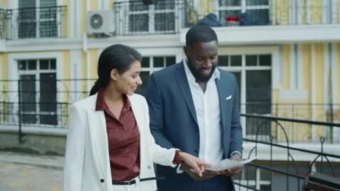 Dışarıda belgeleri inceleyen gülümseyen bir çift. Takım beşlik çakıyor.