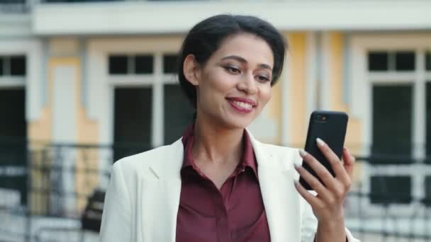 Sonriente mixta mujer de la raza de vídeo de chat fuera. Señora mirando pantalla del teléfono — Vídeos de Stock