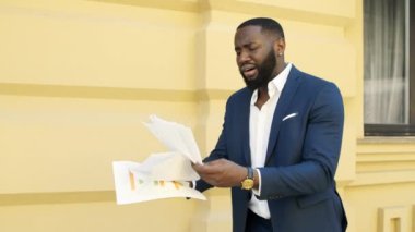 Kızgın işadamı dışarıda belgeleri kontrol ediyor. Afro adam kağıtlarda hata buldu