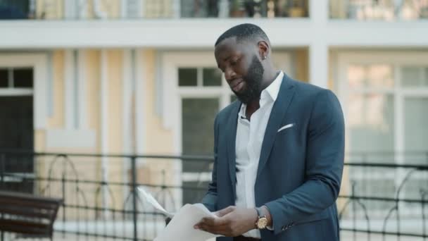Homme d'affaires afro-américain déçu lisant des documents en plein air. — Video