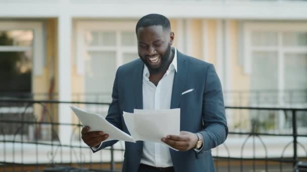 外で書類を調べる幸せなビジネスマンだ。屋外に立つアフロ男. — ストック動画