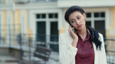 Sakin bir iş kadını dışarıda telefonla konuşuyor. Akıllı telefon kullanan odaklanmış bir kadın.