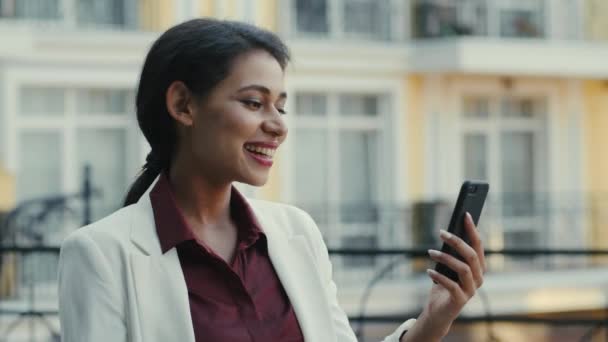 Mujer de negocios de raza mixta que tiene chat de vídeo al aire libre. Mujer sonriente hablando por teléfono — Vídeos de Stock