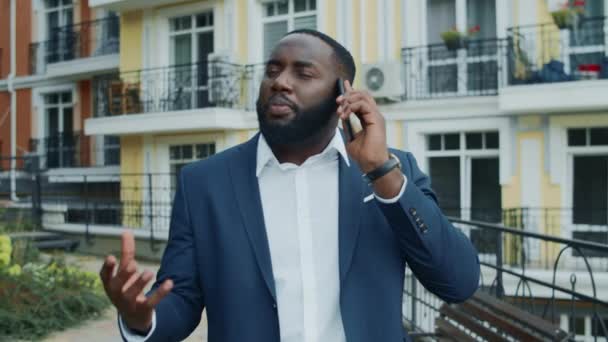 アフリカのビジネスマンが都市部の通りで携帯電話を。外を歩くアフロ男 — ストック動画