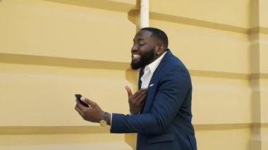 Gülümseyen iş adamı görüntülü aramada konuşuyor. Cep telefonundan konuşan afro adam.