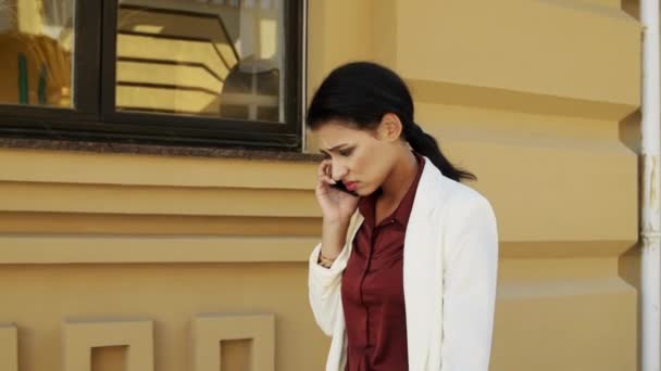 Stresli karışık ırk kadın profesyonel açık havada telefonla yürüyor.. — Stok video