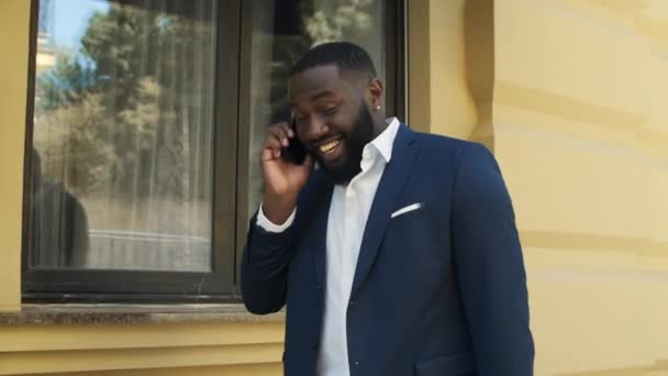 Happy african man walking on street. Young businessman talking on cellphone. — Stock Video