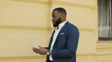 Afrikalı işadamı bir tomar dolarla eğleniyor. Nakitle oynayan adam.