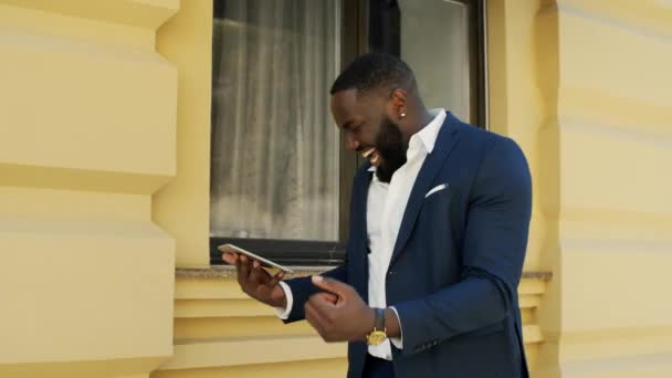 Afro επιχειρηματίας δακτυλογράφηση σε tablet σε εξωτερικούς χώρους. Αφρικανός που περπατάει στον αστικό δρόμο — Αρχείο Βίντεο