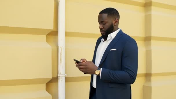 Un hombre de negocios africano serio mandando mensajes al aire libre. Mensaje de escritura de hombre de negocios — Vídeos de Stock