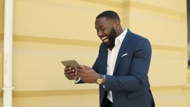 Erfolgreicher afrikanischer Geschäftsmann läuft mit Tablet-Computer auf Stadtstraße. — Stockvideo