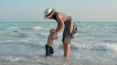 Deniz kıyısından gelen mutlu anne ve çocuk. Suda oturan tatlı çocuk..