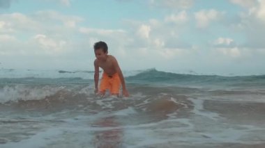 Kumsalda günbatımının tadını çıkaran mutlu genç adam. Deniz kıyısında dalgaları yakalayan neşeli çocuk..