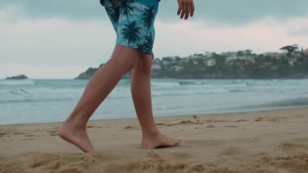 夏を海辺で過ごす無名の少年。海岸を歩く無名の男. — ストック動画