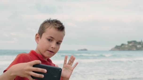Skupiony chłopak robiący selfie na smartfonie na plaży. Facet relaksujący się nad morzem. — Wideo stockowe