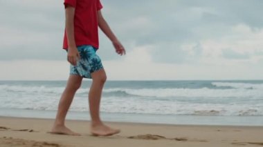 Yazın sahilde eğlenen kimliği belirsiz bir çocuk. Deniz kenarında yürüyen tanınmayan bir adam..