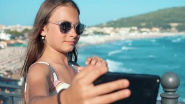 Mutlu kız dışarıda selfie çekiyor. Dışarıda cep telefonuyla el sallayan genç kadın..