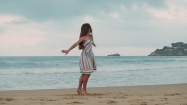 Mutlu kız tatilini deniz kıyısında geçiriyor. Kıyı şeridinde dans eden genç kadın.