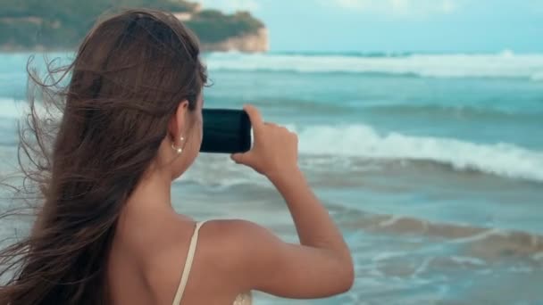 Radosna dziewczyna ciesząca się krajobrazem na wybrzeżu. Nastolatek korzystający z telefonu komórkowego na plaży. — Wideo stockowe