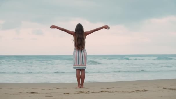 Junge Frau hebt Arm am Meer. Unbekümmertes Mädchen genießt Sonnenaufgang am Strand. — Stockvideo