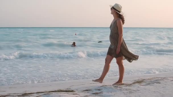 Frau bleibt mit offenen Armen am Strand. Glückliches Mädchen zu Fuß am Meer. — Stockvideo