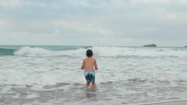 Chico alegre jugando en el mar surf. Adolescente feliz disfrutando del tiempo en la playa. — Vídeo de stock