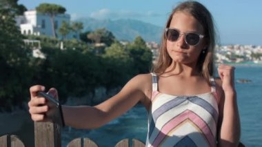 Neşeli kız dışarıda akıllı telefonlara surat asıyor. Kameraya poz veren neşeli genç..