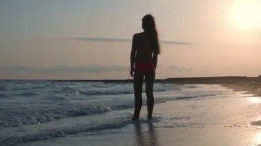 Kumsalda zaman geçiren rahat bir kadın. Deniz dalgalarına bakan bir kız..