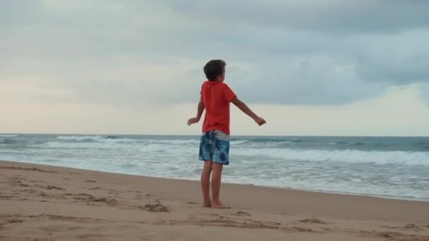 Chico feliz relajándose en la playa. Chico despreocupado disfrutando de vacaciones de verano en la playa. — Vídeos de Stock