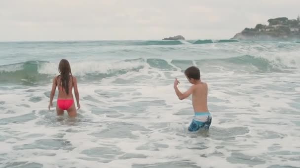 Adolescentes sonrientes nadando en la playa. Niños felices jugando en olas. — Vídeos de Stock