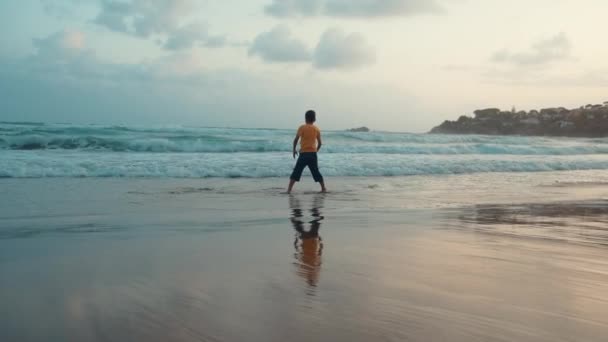 Szczęśliwy chłopiec cieszący się wakacjami nad morzem. Wesoły facet tańczący na plaży.. — Wideo stockowe