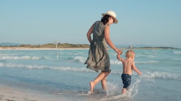 Kobieta ciesząca się rodzinnym weekendem nad morzem. Matka i syn spacerujący po brzegu morza. — Wideo stockowe