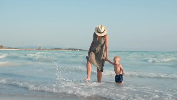 Leende kvinna och son har kul vid kusten. Mamma och barn leker i vågor. — Stockvideo