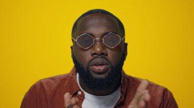 Yakışıklı afro adamın portresi, sarı arka planda kameraya hava öpücüğü gönderiyor..