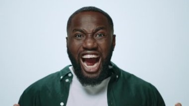 Stüdyoda pozitif duygularla poz veren korkmuş Afrikalı adamın portresi..