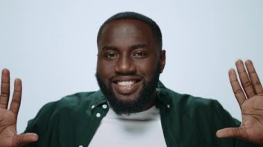 Afro-Amerikan bir adamın açık arkaplanda komik suratlar yaptığı portresi. 