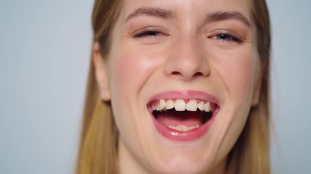Closeup frumoasă femeie fericită zâmbind pe fundal gri în studio . — Videoclip de stoc