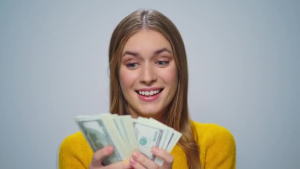 Retrato de jovem sorrindo mulher contando dinheiro em fundo cinza no estúdio. — Vídeo de Stock