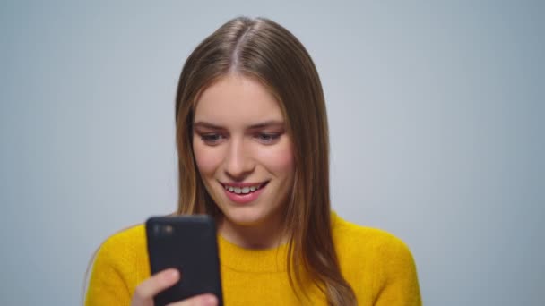 Πορτρέτο της ελκυστικής χαμογελαστή γυναίκα χρησιμοποιώντας το smartphone σε γκρι φόντο. — Αρχείο Βίντεο