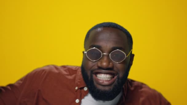 Zbliżenie pozytywny afrykański amerykański facet w okulary taniec w żółty tło — Wideo stockowe