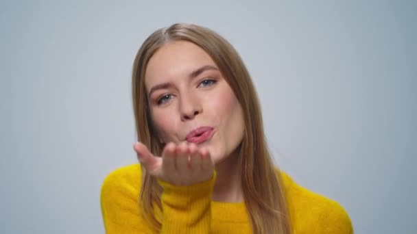 Портрет позитивной женщины, посылающей воздушный поцелуй в камеру на сером фоне. — стоковое видео