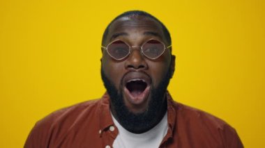 Sarı arka planda poz veren şaşırmış Afrikalı Amerikalı adamın portresi.. 