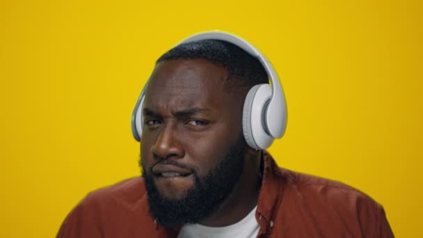 Retrato de hombre africano feliz bailando en auriculares sobre fondo amarillo. — Vídeos de Stock