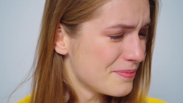 Närbild gråtande kvinna poserar med sorgligt humör på grå bakgrund i studio. — Stockvideo
